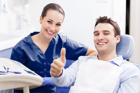 Male patient in dental chair giving thumbs up
