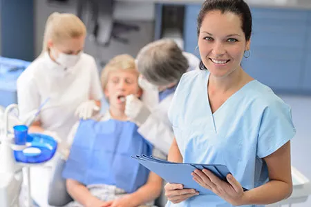Office assistant holding files and a patient in dental chair